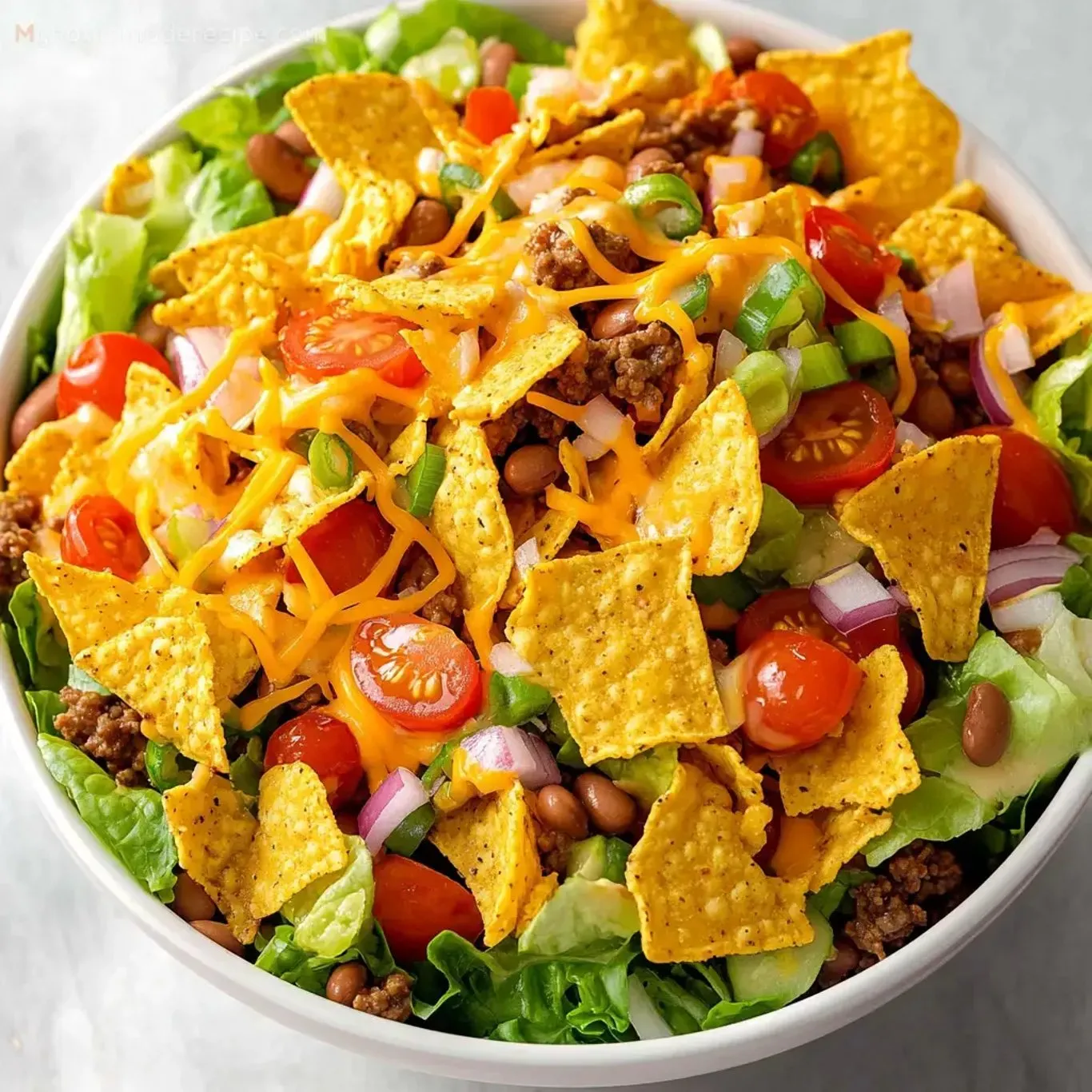 A bowl of salad with chips and beans.