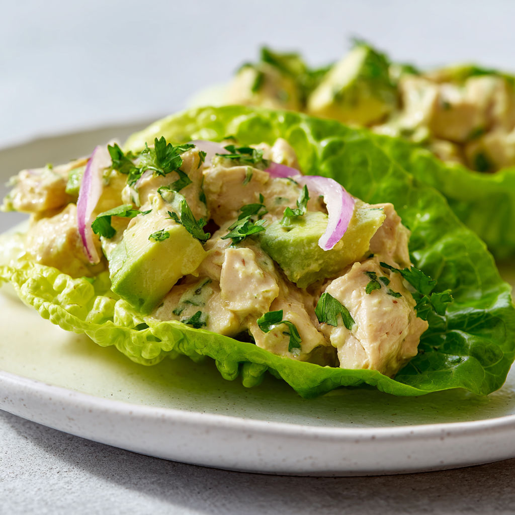 Un mélange croquant de laitue, poulet, avocat et herbes sur une assiette colorée.