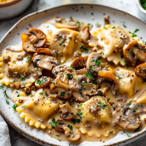 Assiette de ravioles nappées de sauce crémeuse aux champignons, décorée de persil et de poivre.