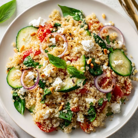 Un grand plat avec quinoa, ricotta, épinards et oignons rouges joliment servi.