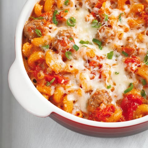 Un plat de macaronis aux tomates et saucisses italiennes présenté dans un plat en verre.