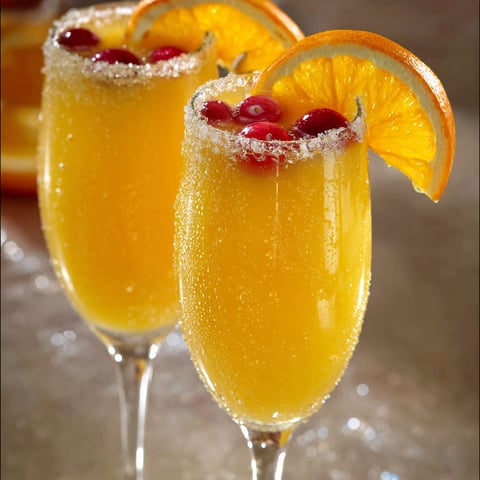 Des verres remplis d’un punch de Noël fait maison, joliment agrémenté de fruits rouges et de citron pour une touche festive.