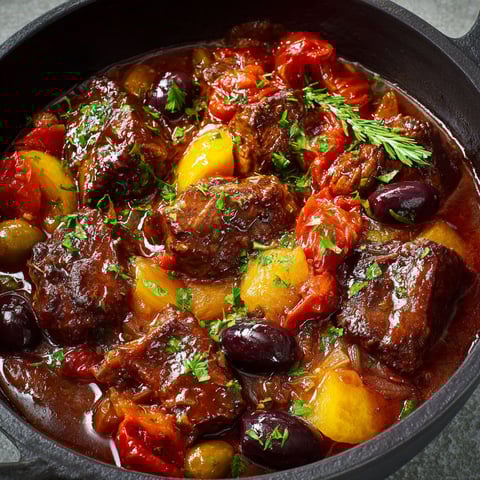 Un savoureux plat de daube niçoise au bœuf servi dans un bol en fonte noir.