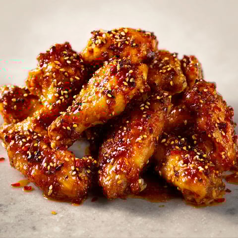 Ailes de poulet posées sur marbre, avec miel, citron et sésame dessus.